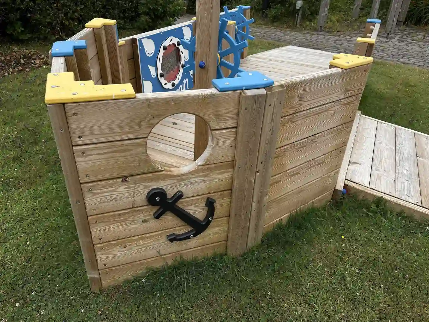 The bow of the All Ability Tug Boat, featuring a black anchor graphic, a circular porthole, and an accessible ramp to the side.