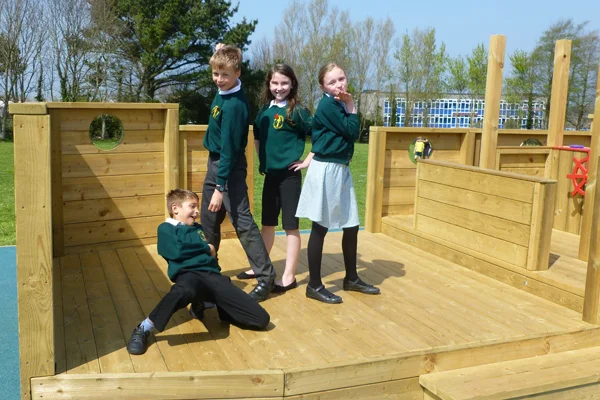 Four school children in uniform posing and playing on the deck of the wooden Boat Stage.