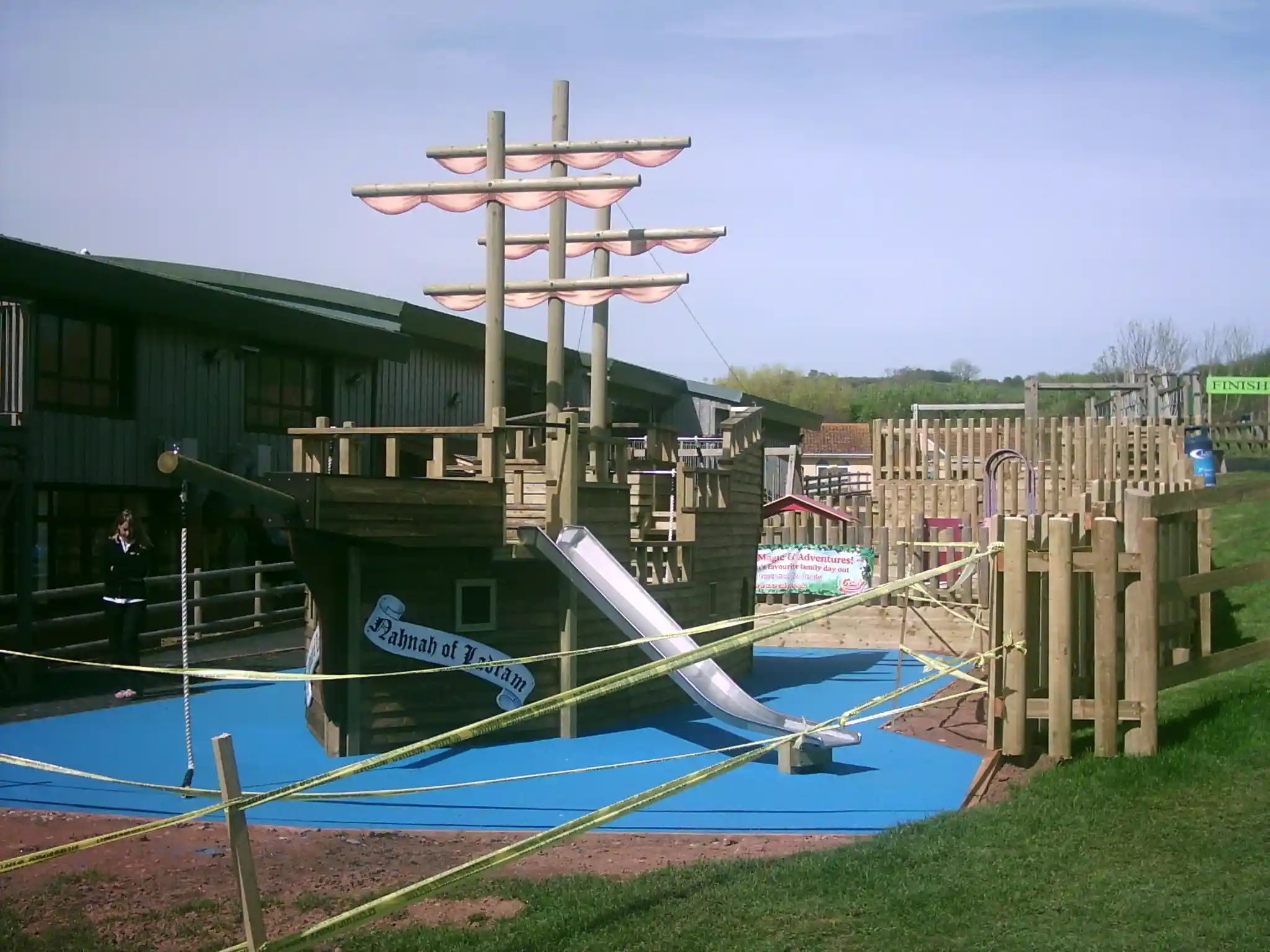 The Coverack Queen, a large wooden pirate ship outdoor play equipment with a slide, in a playground setting.