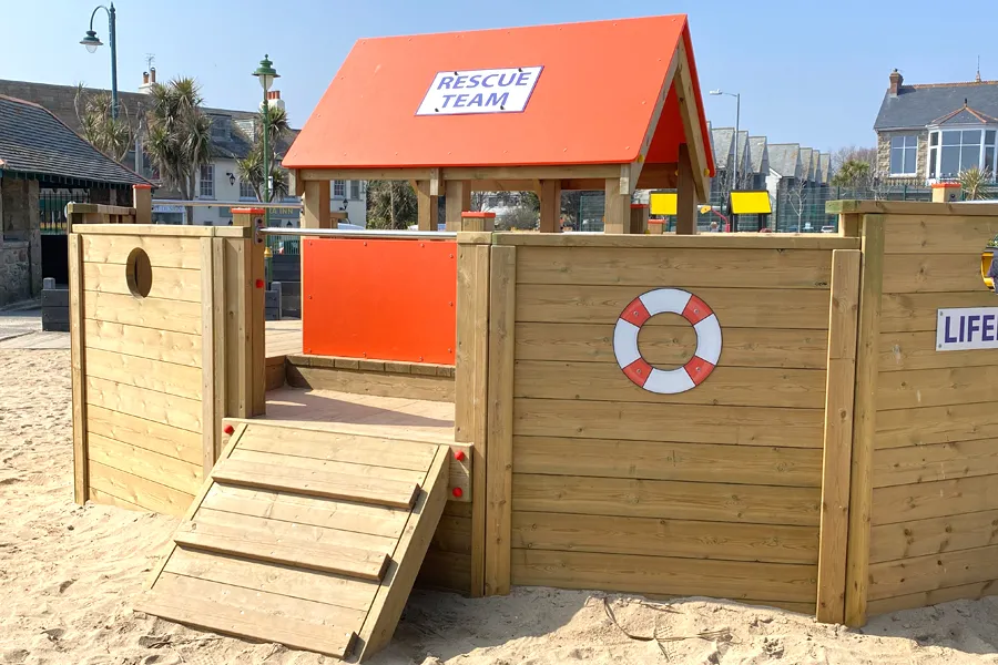 Side view of the Lifeboat play structure showing the "RNLI 17-36" sign, climbing wall, and rope ladder.