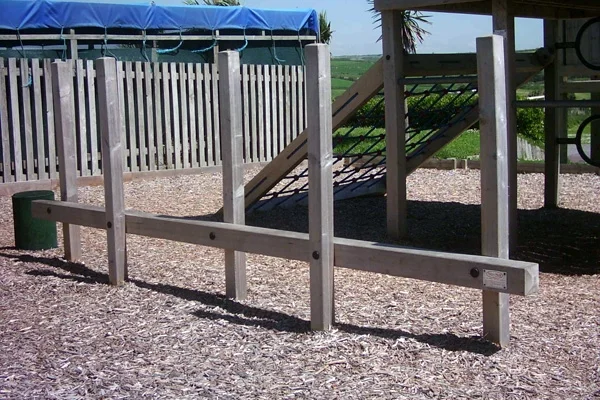 A wooden Post Weave outdoor play equipment installed on a woodchip safety surface in a coastal playground.