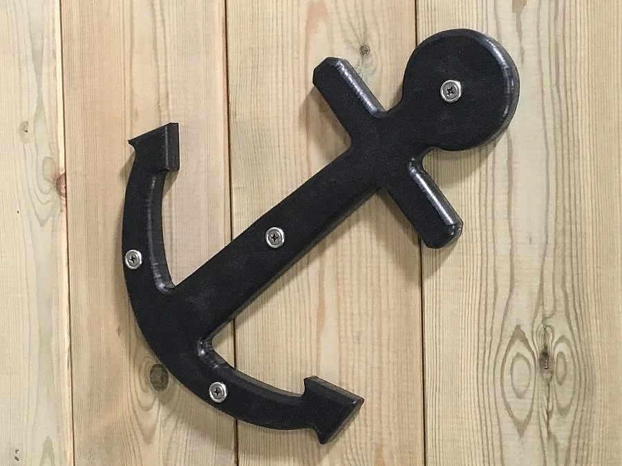 A close-up of a black anchor detail on the side of the St Columb Sailor wooden outdoor play boat.