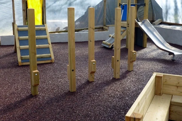 A line of wooden Stepping Stilts installed indoors on a soft, red rubber crumb surface.