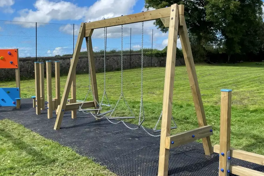 The Swinging Steps outdoor play equipment next to other climbing frames in a school playground on a sunny day.