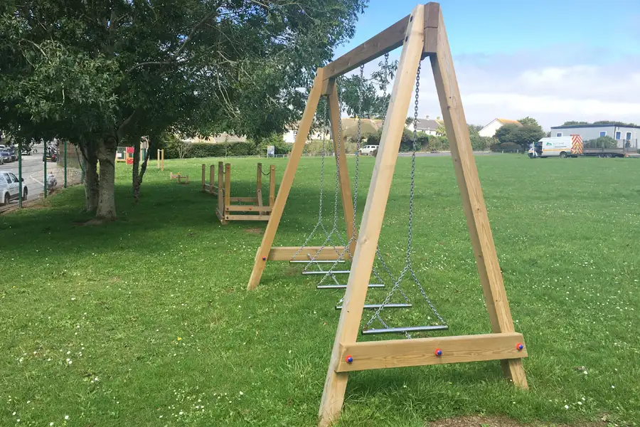 The Swinging Steps wooden A-frame with chain steps, installed as part of a trim trail in a school playground.