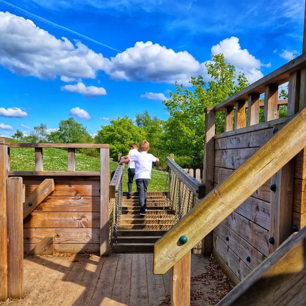 Children crossing rope bridge on timber playground ship