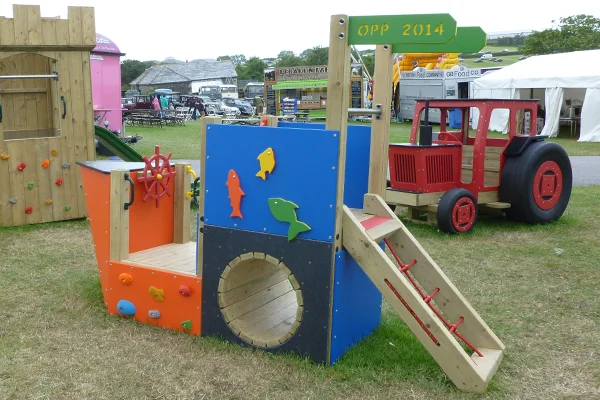 The Trenance Trawler pirate ship playground equipment at an outdoor event, with a red tractor play structure in the background.