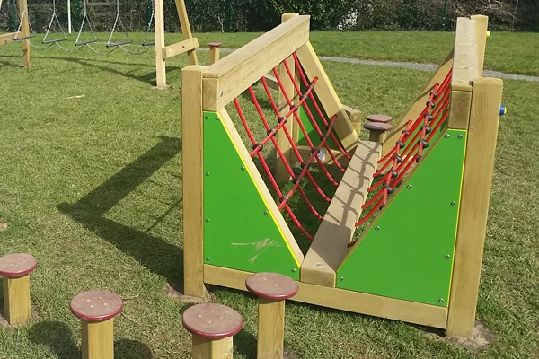 A side view of the V Net Bridge Low Level play equipment, with wooden stepping posts in the foreground.