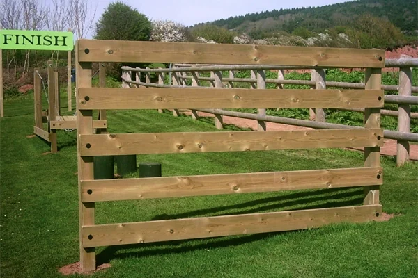 Timber vaulting gate obstacle on outdoor playground trim trail with finish sign