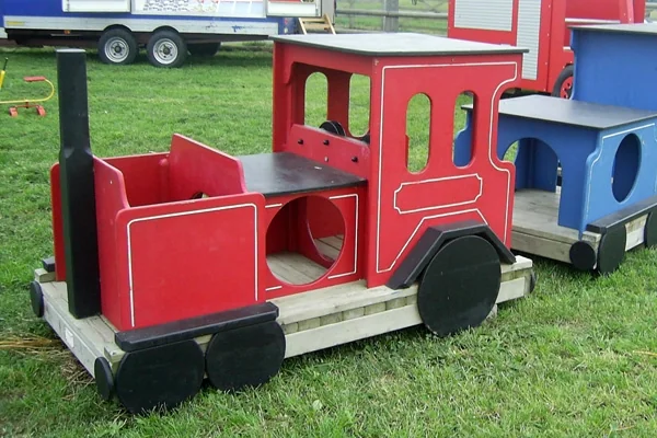 Colorful miniature wooden train engine and carriage on grass, designed for children’s outdoor play.