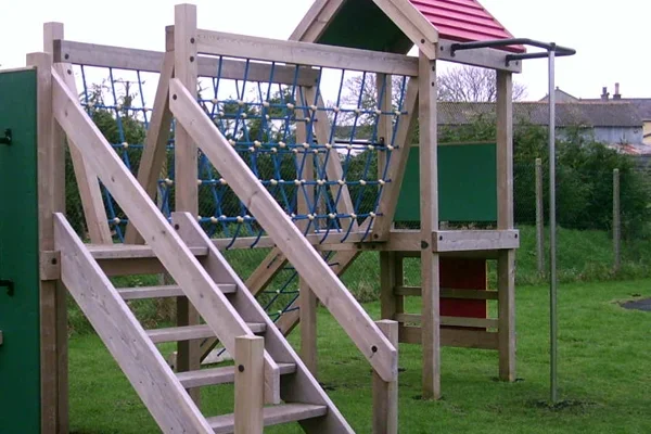Timber fireman’s pole climbing play equipment in a wooden playground structure for outdoor play