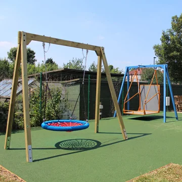 Timber special needs accessible swing in a bespoke wooden playground for inclusive play